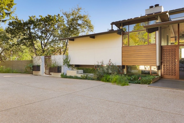 view of home's exterior with a patio, a chimney, and fence
