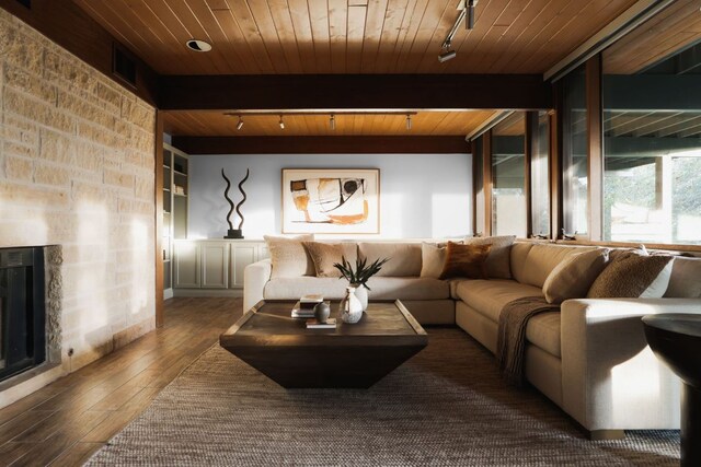 living room featuring track lighting, visible vents, a stone fireplace, hardwood / wood-style floors, and wood ceiling
