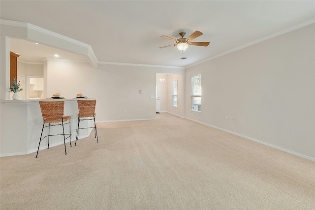 interior space with ornamental molding, light colored carpet, baseboards, and a ceiling fan