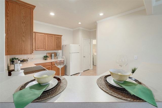 kitchen with brown cabinetry, recessed lighting, freestanding refrigerator, and crown molding