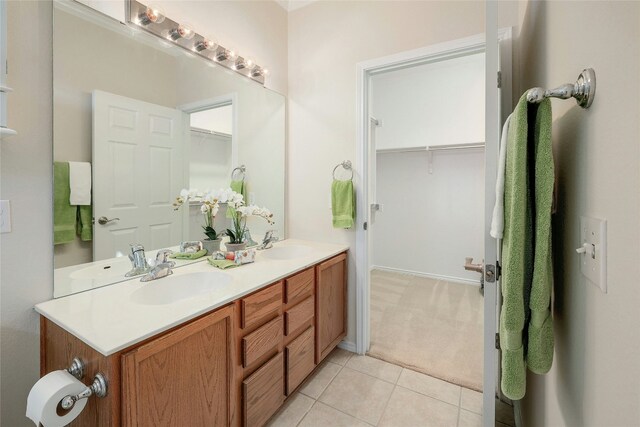 full bath with a spacious closet, tile patterned flooring, and a sink