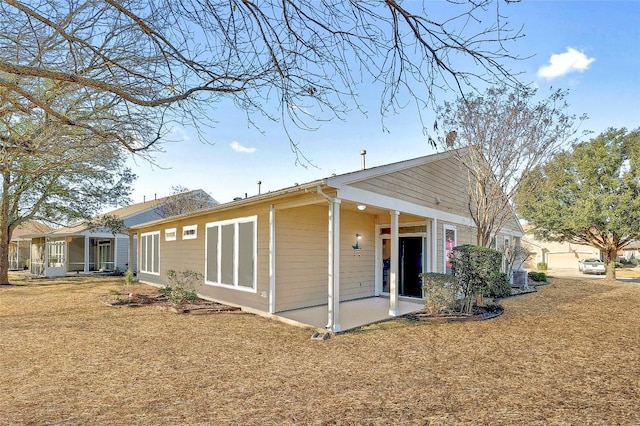 back of property with a sunroom, central AC, and a lawn