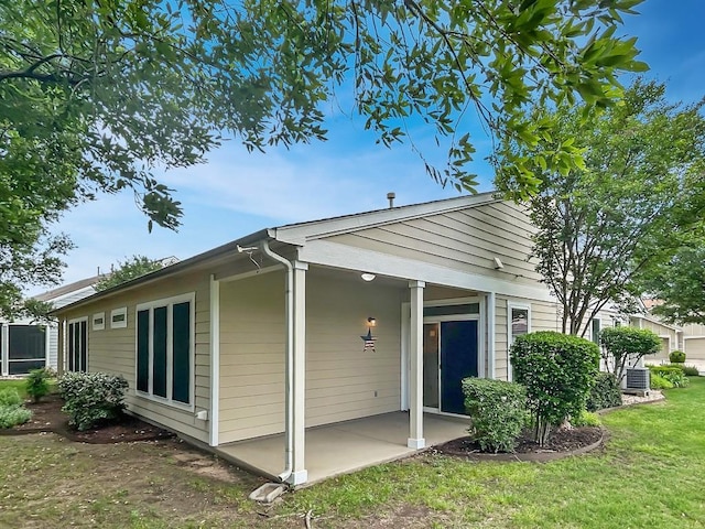 view of side of property with a lawn, central AC, and a patio area