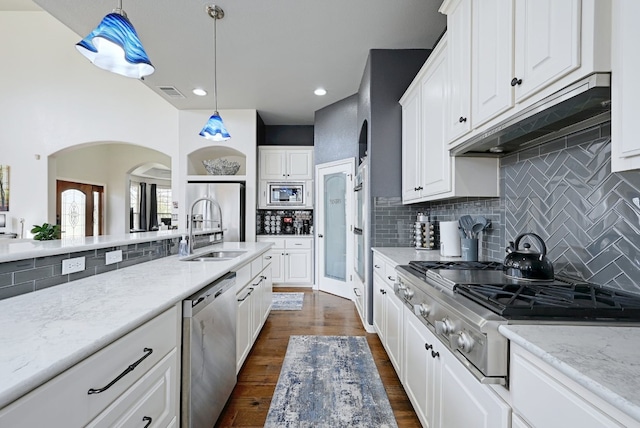 kitchen with under cabinet range hood, dark wood-type flooring, a sink, visible vents, and appliances with stainless steel finishes