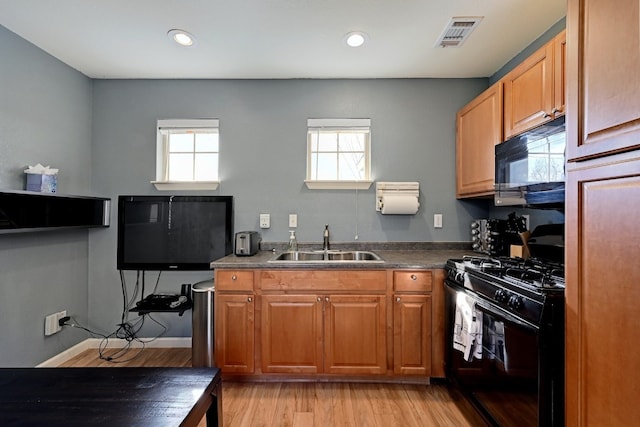 kitchen featuring recessed lighting, visible vents, light wood-style flooring, a sink, and black appliances