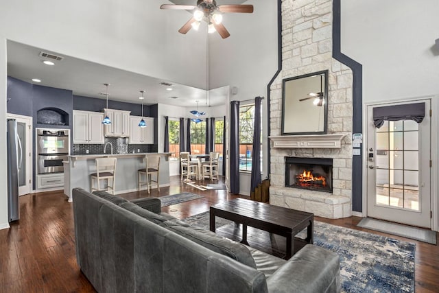 1601 Forest St, Georgetown, TX 78626 - living room with a ceiling fan, dark wood-type flooring, a fireplace, a towering ceiling, and baseboards
