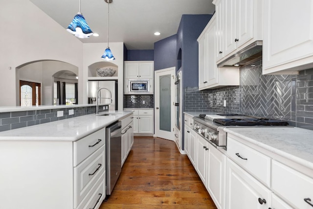 1601 Forest St, Georgetown, TX 78626 - kitchen featuring appliances with stainless steel finishes, decorative backsplash, under cabinet range hood, white cabinets, and decorative light fixtures