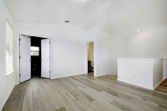 unfurnished room with baseboards, visible vents, light wood-type flooring, and lofted ceiling