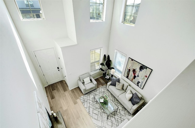 living room with light wood-style flooring and a towering ceiling