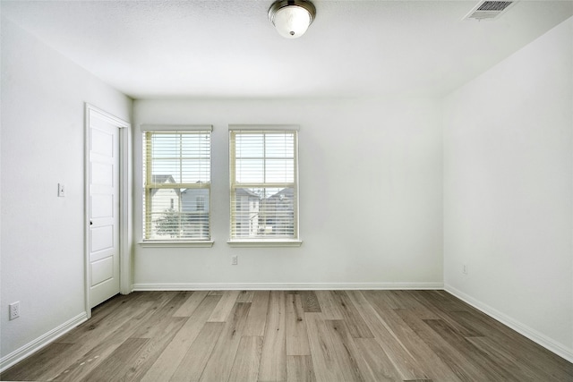 unfurnished room featuring visible vents, baseboards, and wood finished floors