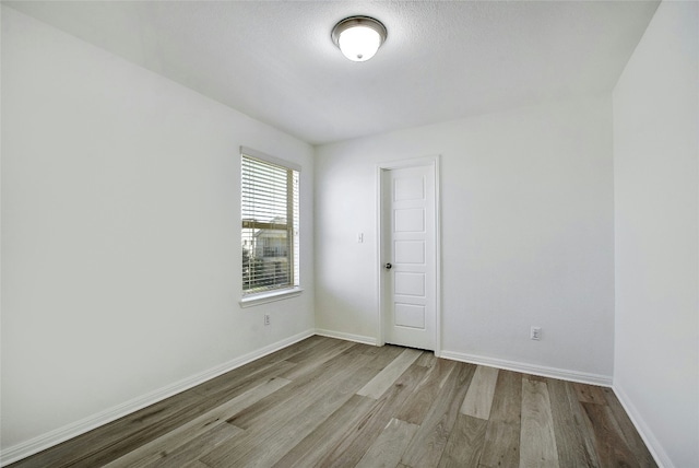spare room with baseboards and wood finished floors