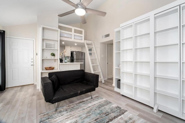 sitting room featuring high vaulted ceiling, light wood finished floors, visible vents, and a ceiling fan