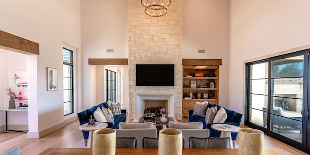 179 Lagrange Dr, Fredericksburg, TX 78624 - living room with a high ceiling, a fireplace, healthy amount of natural light, light wood-type flooring, and a chandelier