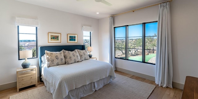 bedroom featuring baseboards, multiple windows, and light wood finished floors