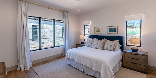 bedroom featuring light wood-type flooring, multiple windows, and baseboards