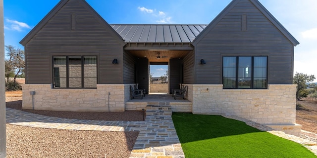 view of front of property featuring a standing seam roof, stone siding, and metal roof