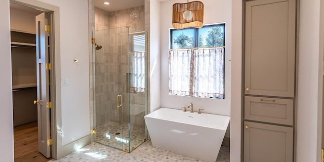 full bath featuring a stall shower, a freestanding tub, and plenty of natural light