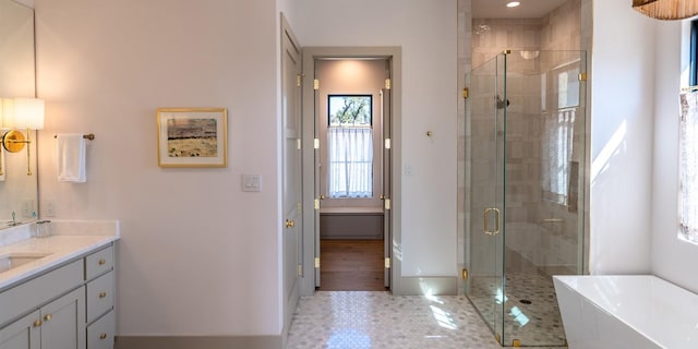 bathroom with baseboards, a freestanding bath, a shower stall, and vanity