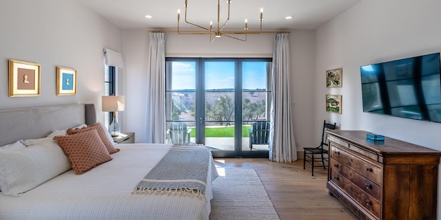 bedroom featuring an inviting chandelier, access to outside, wood finished floors, and recessed lighting