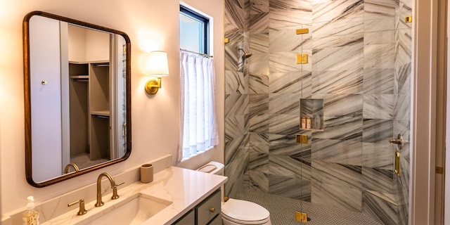 full bathroom with toilet, a tile shower, and vanity