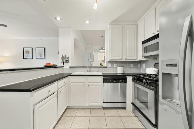 kitchen featuring tasteful backsplash, dark countertops, appliances with stainless steel finishes, white cabinetry, and a sink