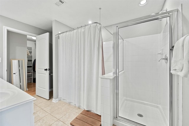 bathroom featuring a spacious closet, a stall shower, visible vents, and tile patterned floors