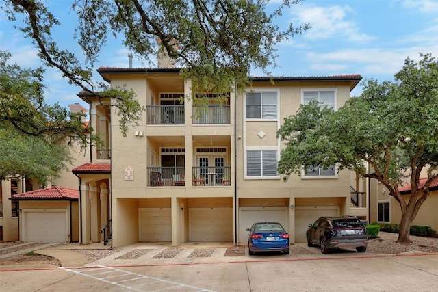 view of front of house with a garage, driveway, a tile roof, and stucco siding