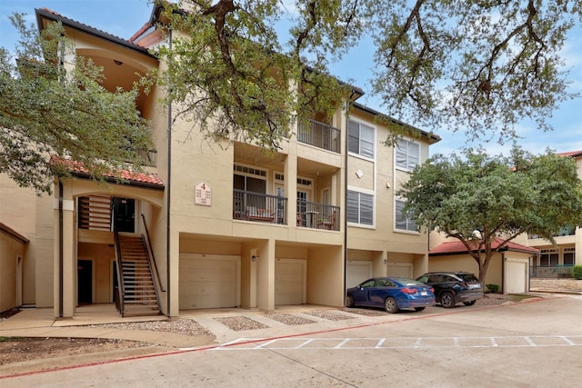 view of building exterior featuring a garage, driveway, and stairs