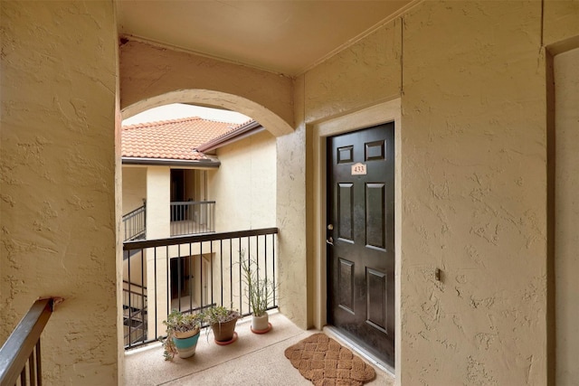 property entrance featuring a balcony and stucco siding