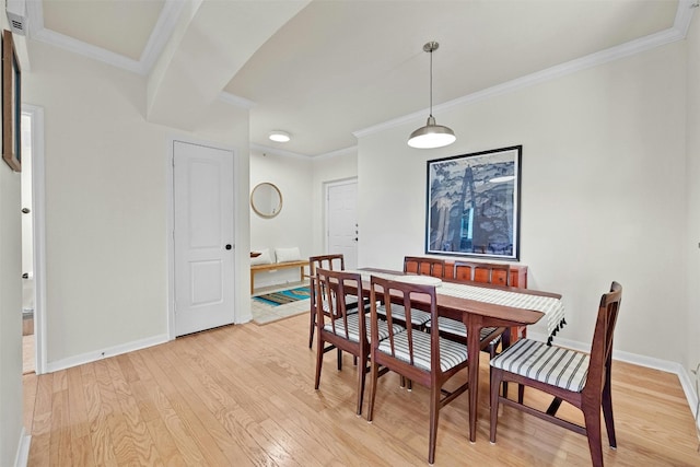 dining room featuring baseboards, crown molding, and light wood finished floors