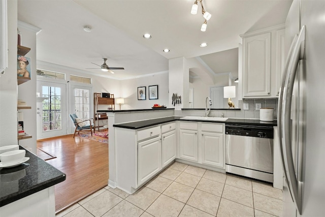 kitchen featuring appliances with stainless steel finishes, a peninsula, white cabinetry, a sink, and light tile patterned flooring