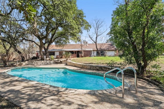 outdoor pool with a yard and a patio