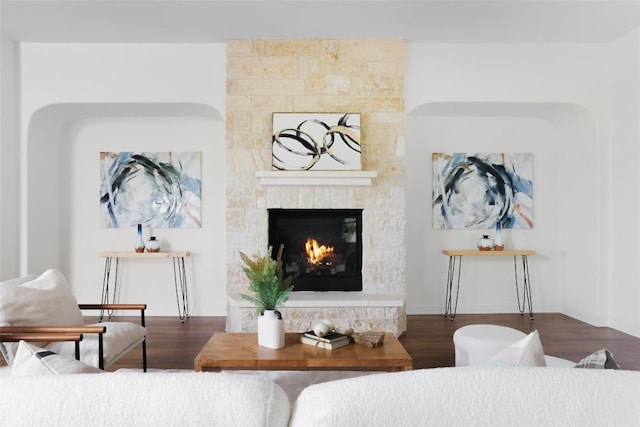 living area with a stone fireplace, baseboards, and wood finished floors