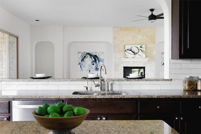 kitchen featuring a sink, a ceiling fan, light stone counters, and stainless steel dishwasher