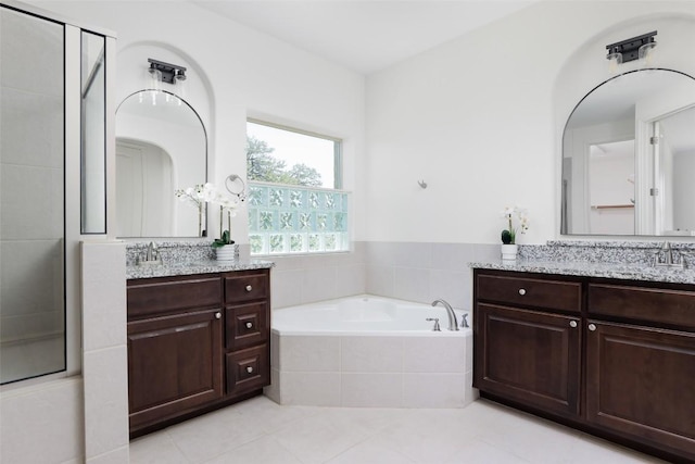 full bathroom featuring a sink, a garden tub, two vanities, and a stall shower