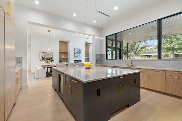 kitchen featuring light stone counters, light wood-style floors, a large island, modern cabinets, and a sink