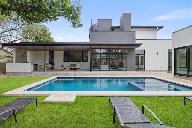 back of house featuring stucco siding, a patio, a lawn, and a pool with connected hot tub