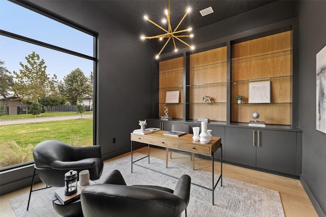 home office with a notable chandelier, baseboards, and light wood-type flooring