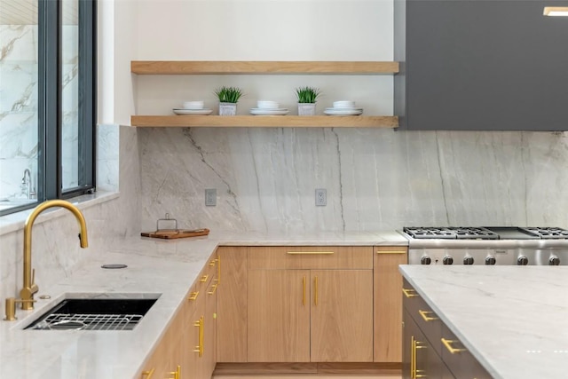 kitchen featuring tasteful backsplash, a sink, light stone countertops, modern cabinets, and open shelves