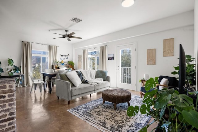 living area featuring finished concrete floors, a healthy amount of sunlight, visible vents, and ceiling fan