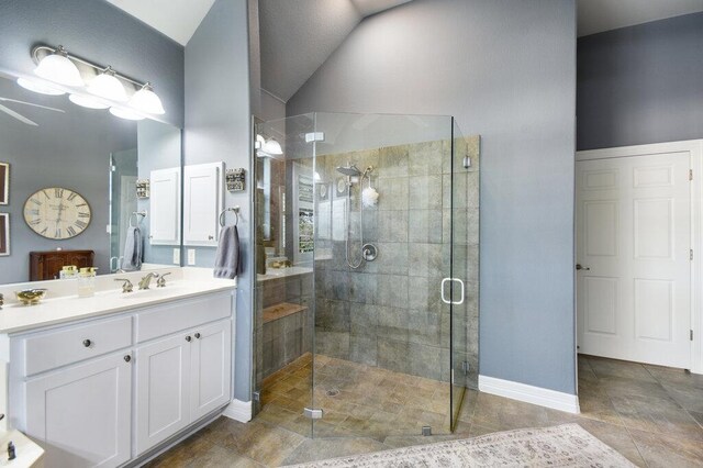 full bath featuring a stall shower, baseboards, vanity, lofted ceiling, and tile patterned flooring