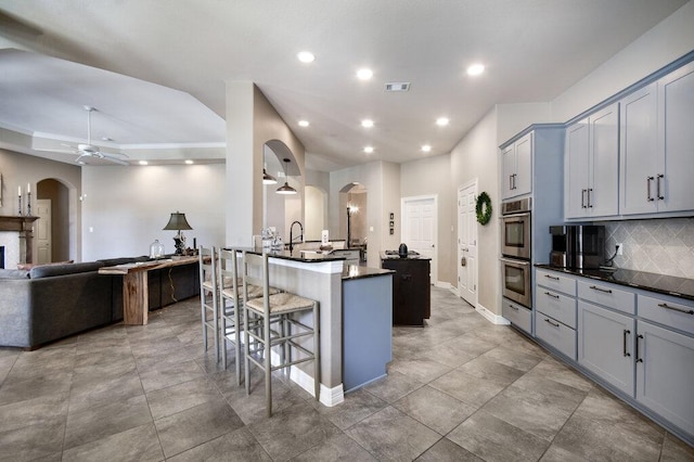 9512 Palmbrook Dr, Austin, TX 78717 - kitchen with a kitchen bar, arched walkways, stainless steel double oven, gray cabinetry, and recessed lighting