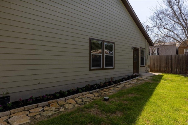 view of property exterior featuring fence and a lawn