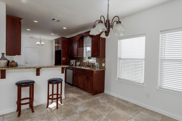 kitchen with visible vents, dishwasher, a kitchen bar, a chandelier, and a sink