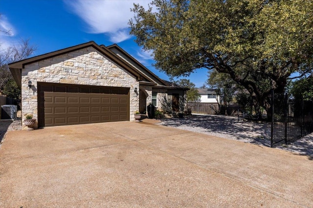 view of front of house featuring a garage, stone siding, concrete driveway, and fence