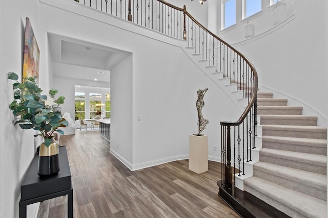 foyer featuring stairs, baseboards, a high ceiling, and wood finished floors