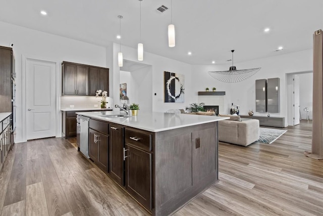 4737 Modena Bay Bnd, Leander, TX 78641 - kitchen featuring a sink, light wood-style flooring, dark brown cabinets, light countertops, and recessed lighting