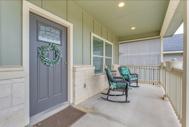 entrance to property with a porch and roof with shingles