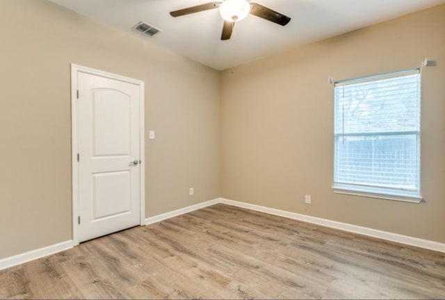 spare room with a ceiling fan, wood finished floors, visible vents, and baseboards