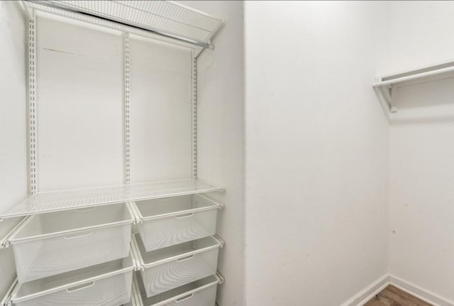 walk in closet with wood finished floors